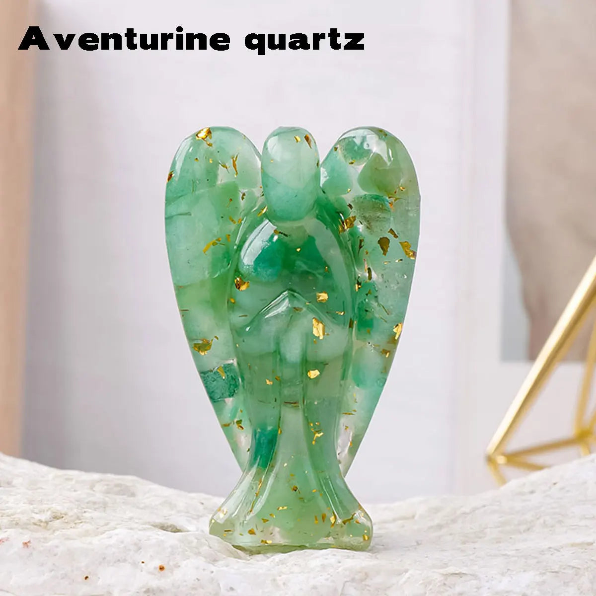 A green aventurine quartz figurine shaped like a guardian angel, resting on a light-colored surface.