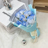 A bouquet of light blue artificial roses wrapped in a teal paper and tied with white ribbon.
