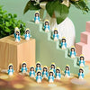 A collection of multicolor mini Virgin Mary statues in blue and white are displayed on a wooden block and steps.