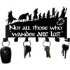 Decorative metal wall-mounted key holder with seven hooks displaying various keys.