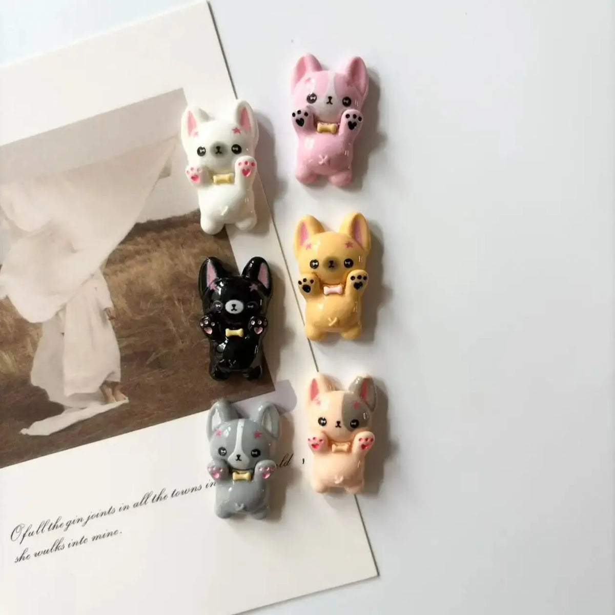 A set of mini puppy refrigerator magnets in pink, white, and yellow colors displayed on a white background.
