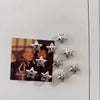 A collection of silver star-shaped decorative fridge magnets arranged on a dark card.
