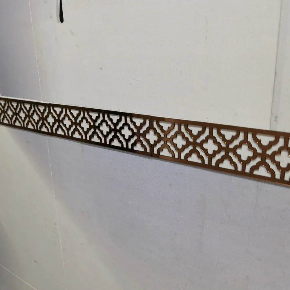 A decorative bronze-colored acrylic mirror wall sticker featuring an intricate geometric pattern used as an edge or corner tr