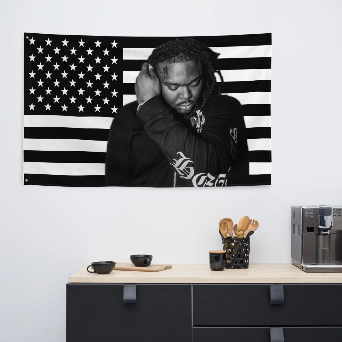A man with dreadlocks is pictured against an American flag tapestry banner.