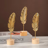 Three golden ginkgo leaf metal decorative sculptures displayed on a white surface.