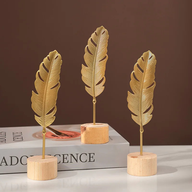 Three golden ginkgo leaf metal decorative sculptures displayed on a white surface.