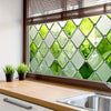A close-up of a window featuring green leaf privacy film with a diamond pattern.