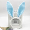 Pair of light blue bunny ear headbands displayed in a white photo frame.