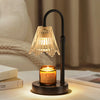 A black lamp with a textured glass shade and candle holder sits on a wooden surface.