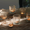 A collection of vintage striped glass votive candle holders resting on draped brown fabric.