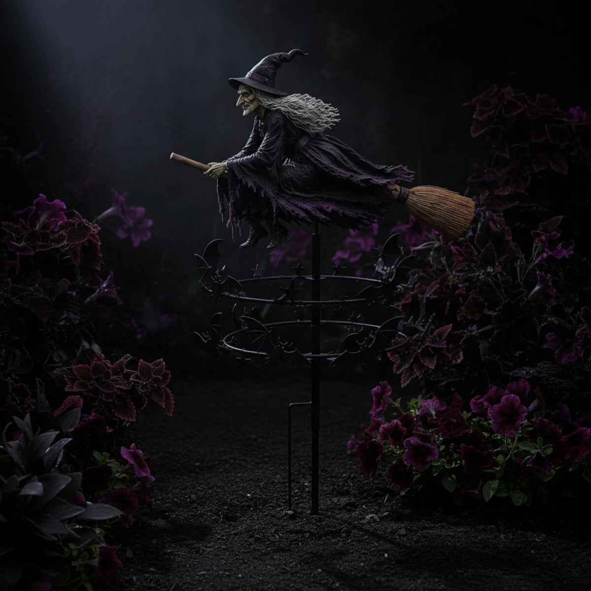 A dark witch figure in a pointed hat and cloak stands atop a metal spinner surrounded by deep purple foliage.