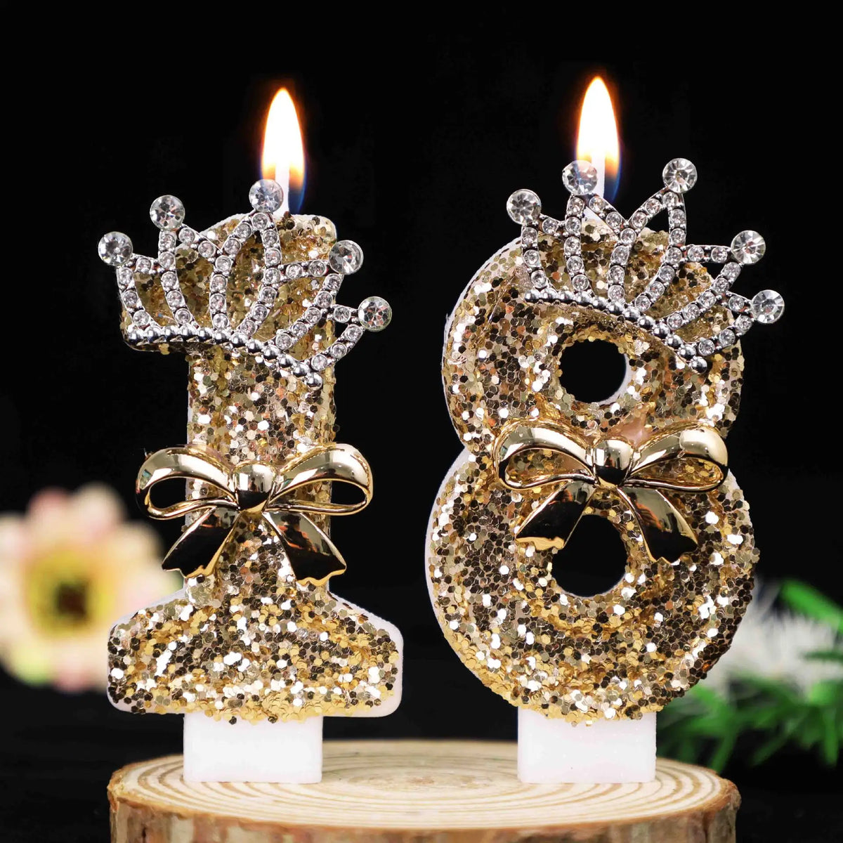 Gold glitter number cake topper candles featuring a rhinestone bow on a wooden base.