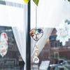 A hanging crystal tree of life sun catcher with colorful crystals suspended by a delicate chain.