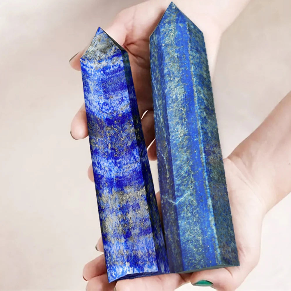 Two polished lapis lazuli crystal towers with blue and gold striations held in a hand.