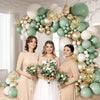 A balloon arch display featuring sage green, gold, and white balloons for events.