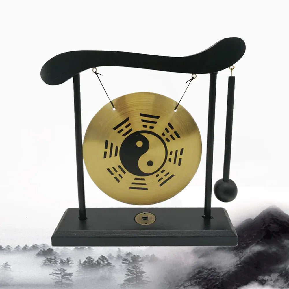 A black desktop zen gong suspended by a cord, featuring a large golden yin-yang symbol.