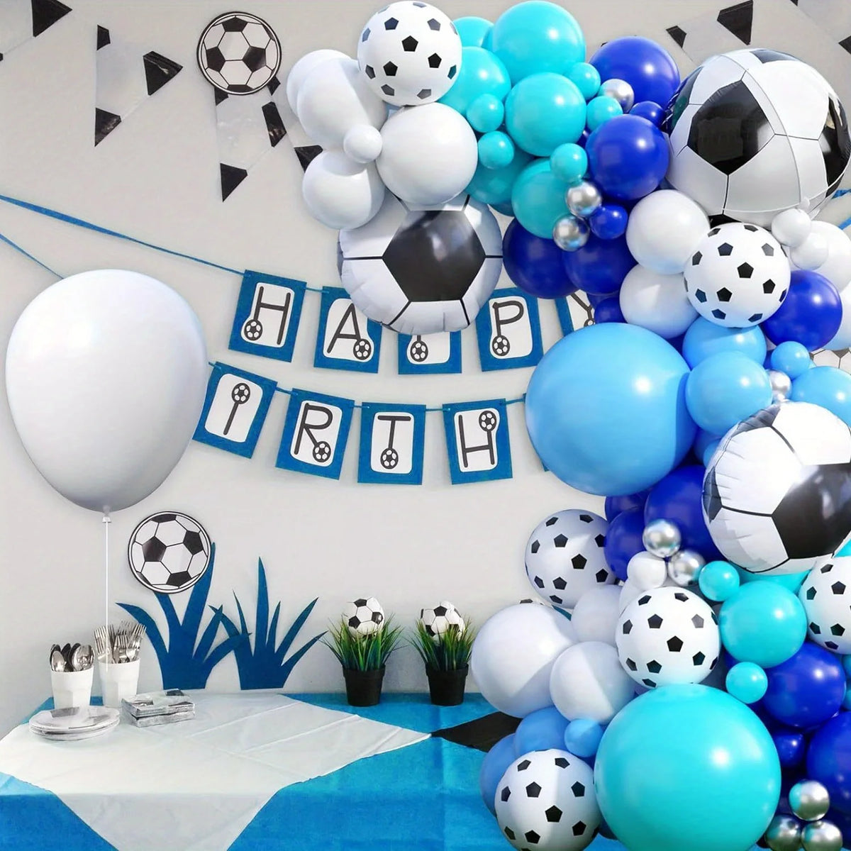 A balloon garland featuring black and white soccer balls and blue balloons for a birthday theme.