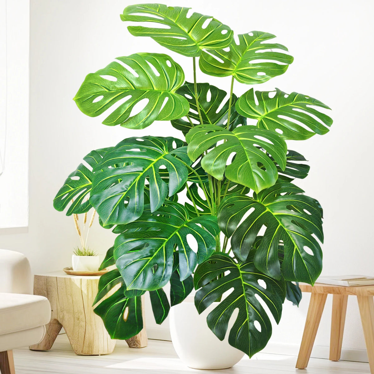 A vibrant artificial monstera plant with large green silk leaves displayed in a white pot on a wooden surface.