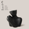 A black ceramic figural vase shaped like an artistic human form.