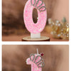 Two pink glitter birthday candles shaped like the numbers 0 and 1 with crown decorations