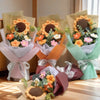A bouquet of handcrafted crochet sunflowers and daisies in various shades of orange, yellow, and pink flowers wrapped in ligh