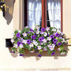 A vibrant bundle of purple and white artificial petunias cascading from a window ledge.