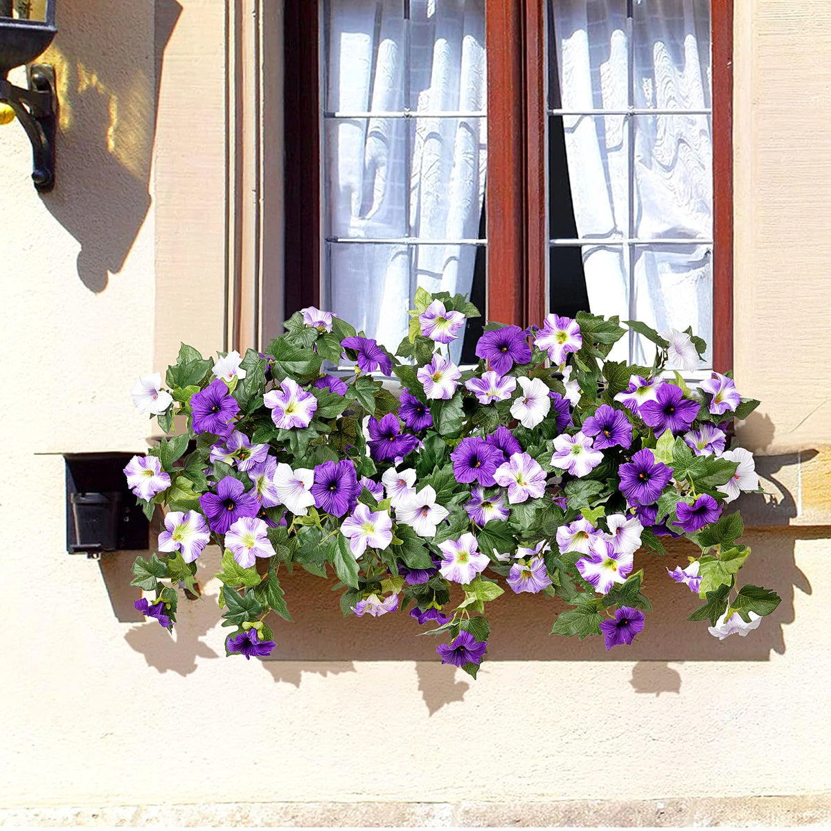A vibrant bundle of purple and white artificial petunias cascading from a window ledge.