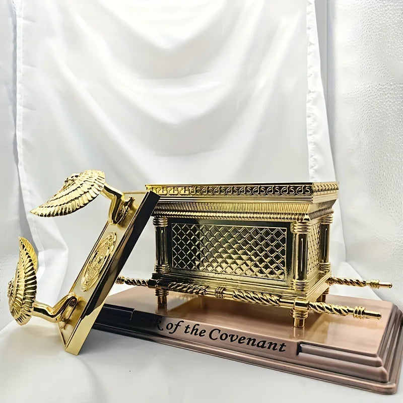 A golden metal statue depicting the Ark of the Covenant resting on a wooden plaque.