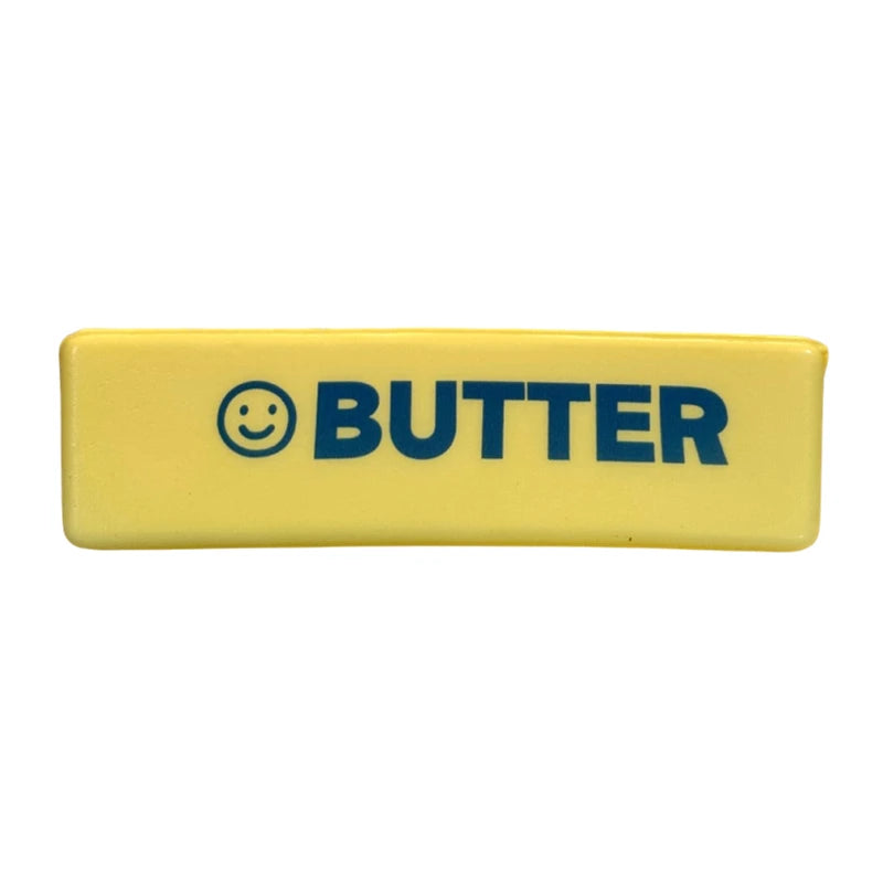 Jouet anti-stress rectangulaire jaune avec le mot BUTTER et un visage souriant imprimés en bleu.