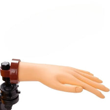 An orange silicone practice hand used for manicure training.