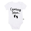 White baby bodysuit with black text that reads Coming Soon