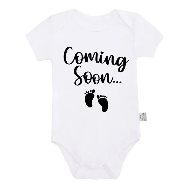 White baby bodysuit with black text that reads Coming Soon