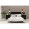 A bedroom setting featuring a black headboard, white bedding, and two wooden wall candle holders on a gray wall.