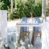 Wooden Mr & Mrs decorative letters for weddings displayed on a rustic table surrounded by white flowers.