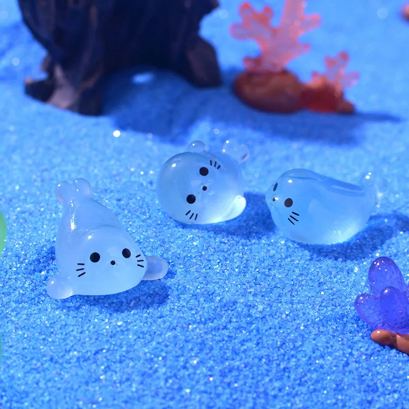 A collection of glowing blue resin sea animal figurines, including a cat and other shapes, resting on a sparkling blue surfac