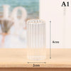 A clear glass cylindrical vase or bottle with vertical ridges, shown on a wooden surface.