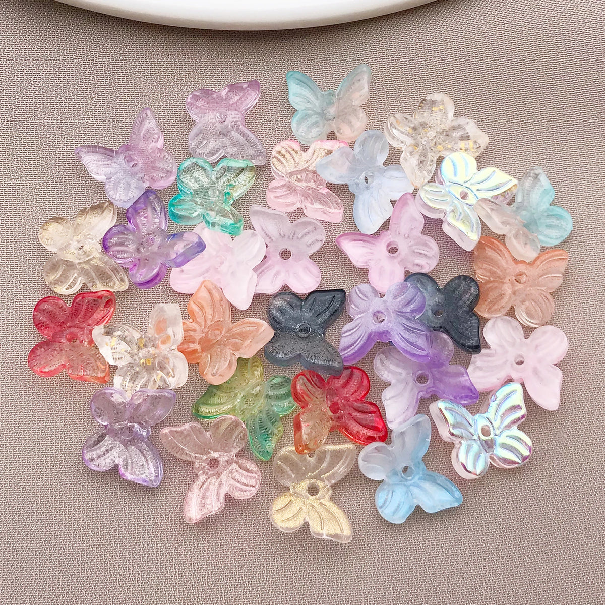 Variedad de cuentas de mariposa de vidrio coloridas esparcidas sobre un fondo neutro