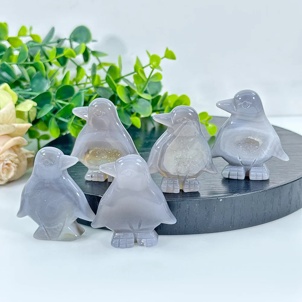 A set of smooth, grey natural agate crystal figurines of doves resting on a dark wooden surface.