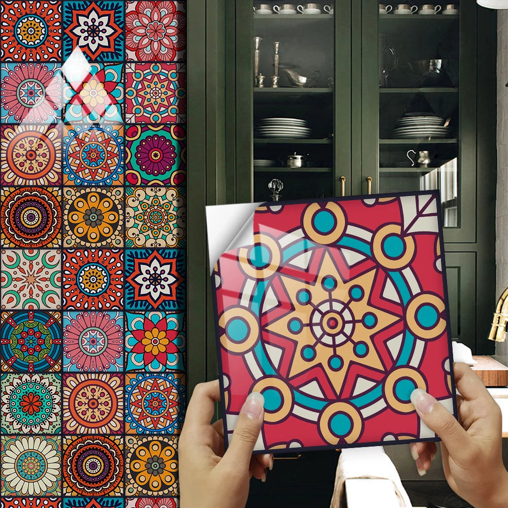 Hands hold a colorful mandala peel and stick wall tile design against a dark green cabinet background.