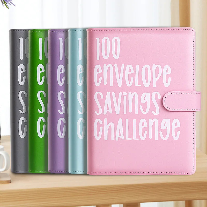 A pink budget savings binder with twelve colored envelopes labeled for a savings challenge.