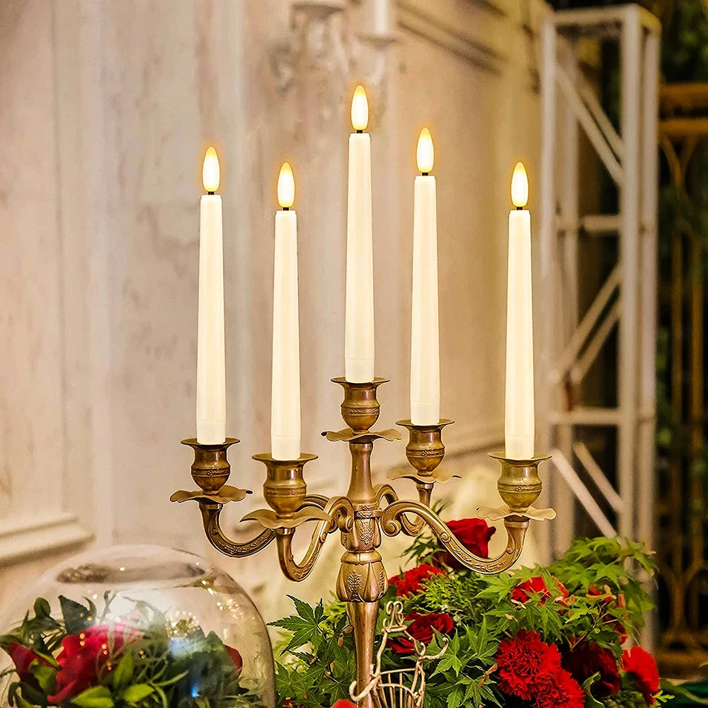 A brass candelabra holds five white pillar candles in a floral arrangement.