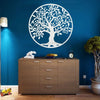 A white vinyl decal of a tree of life silhouette on a blue wall above a wooden cabinet.
