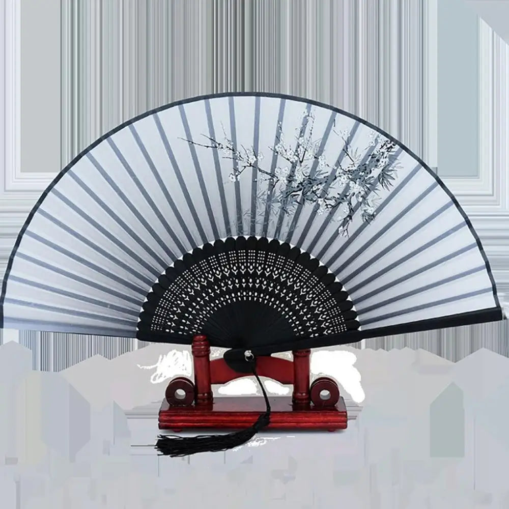 A vintage silk folding fan with black and white striped patterns is displayed on a wooden stand.
