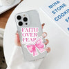 A hand holds a clear phone case featuring the text Faith Over Fear and a pink bow design.