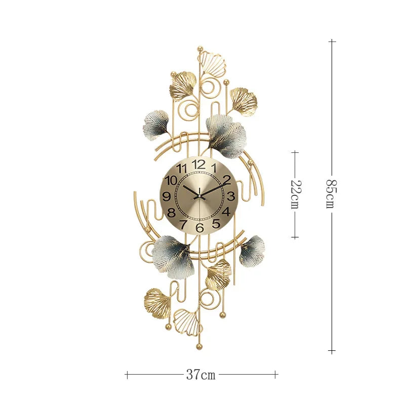 A gold-toned metal wall clock featuring a circular face with Roman numerals and decorative branches resembling ginkgo leaves.