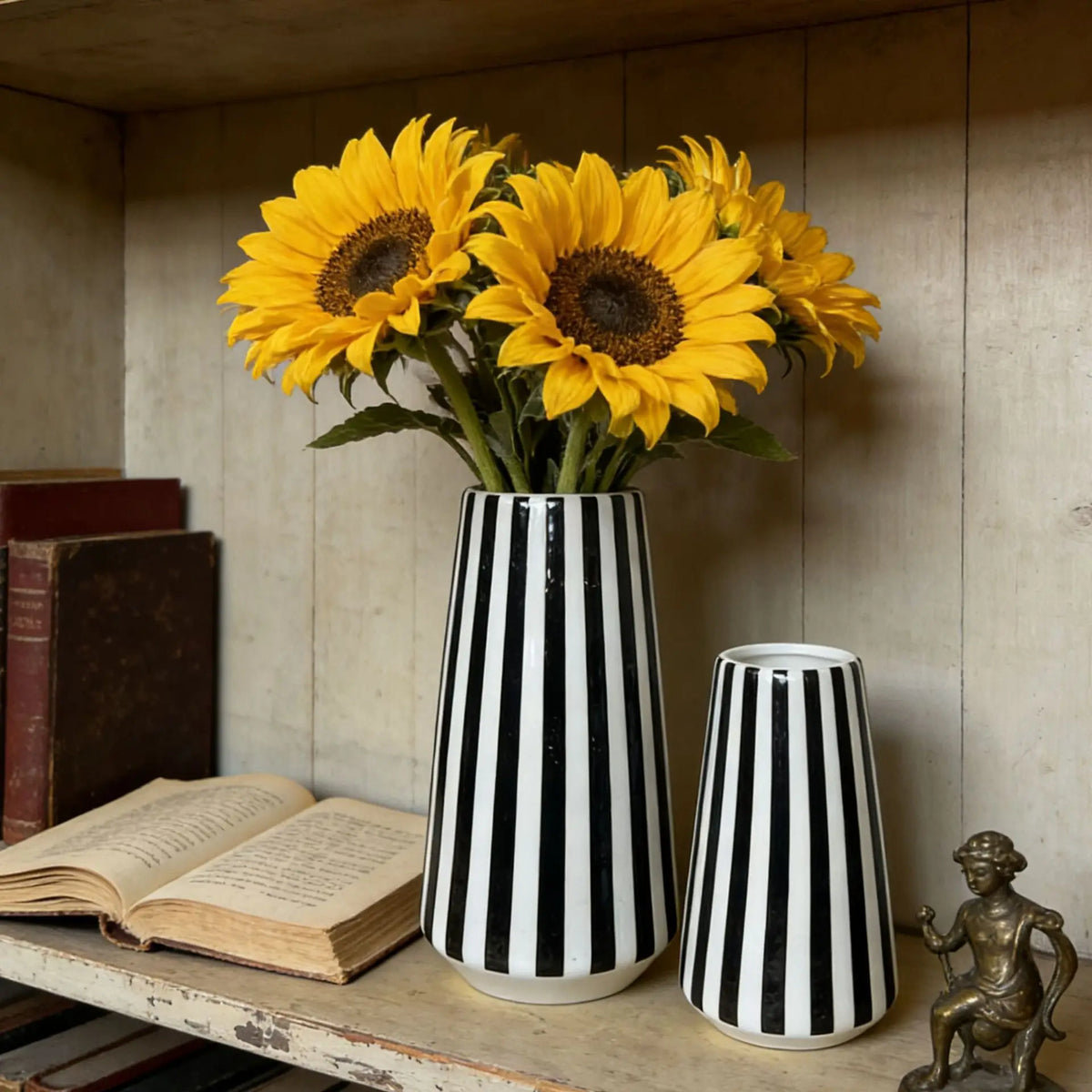 A minimalist black and white checkered ceramic vase filled with bright yellow sunflowers on a wooden shelf.