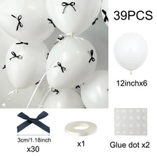 A set of 39 white latex balloons with black ribbon bows and glue dots for decoration
