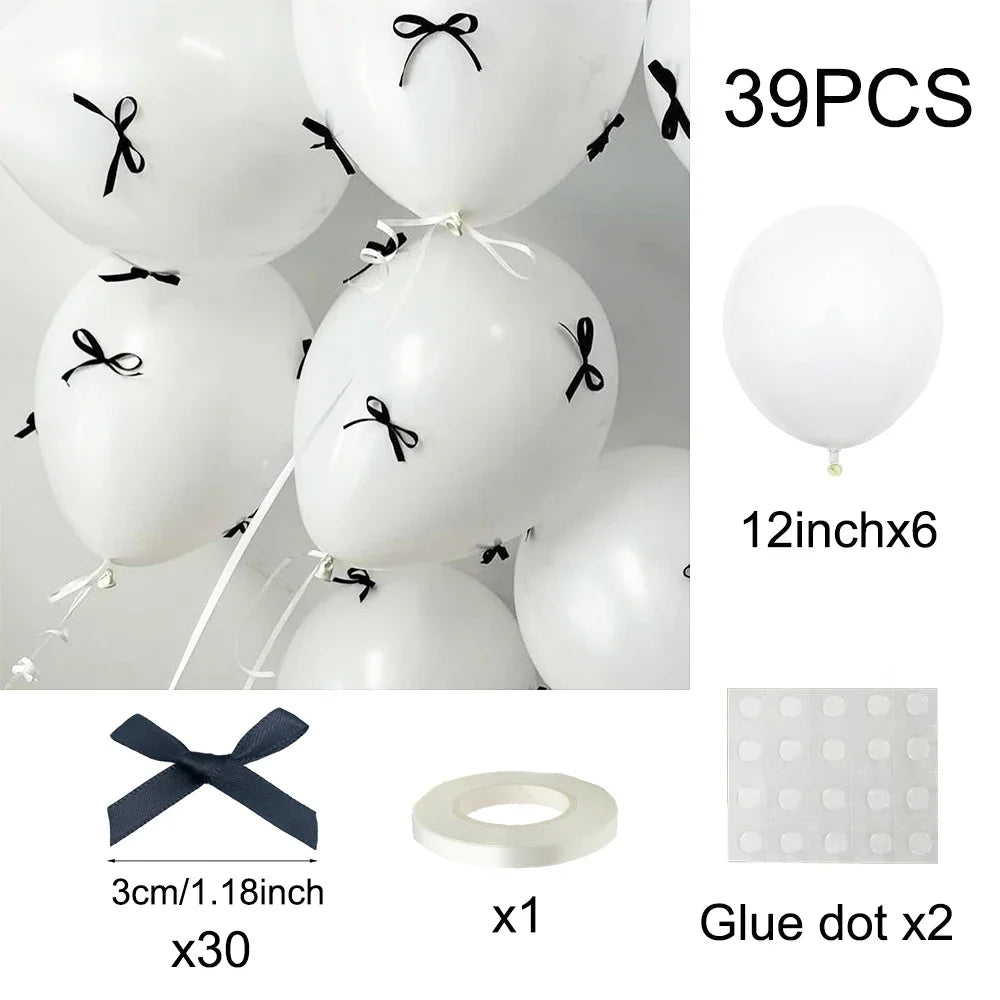 A set of 39 white latex balloons with black ribbon bows and glue dots for decoration
