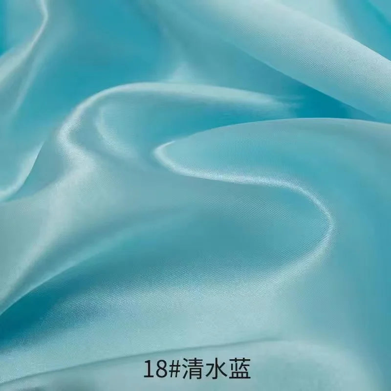 Flowing light blue satin fabric draped in soft folds