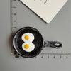 A black food-shaped magnet resembling an egg is placed next to a ruler.